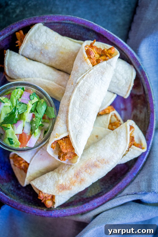 Pinto Bean and Jackfruit Taquitos, a delicious and savory vegan taquito option, served with a dipping sauce.