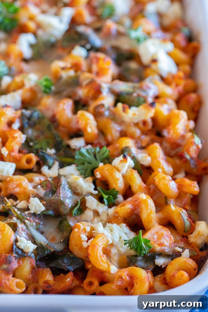 Creamy Spinach Feta Pasta Bake 5 A close-up shot of the finished spinach feta baked pasta in a pan, showcasing the melted, bubbly cheese, vibrant spinach, and perfectly coated pasta.
