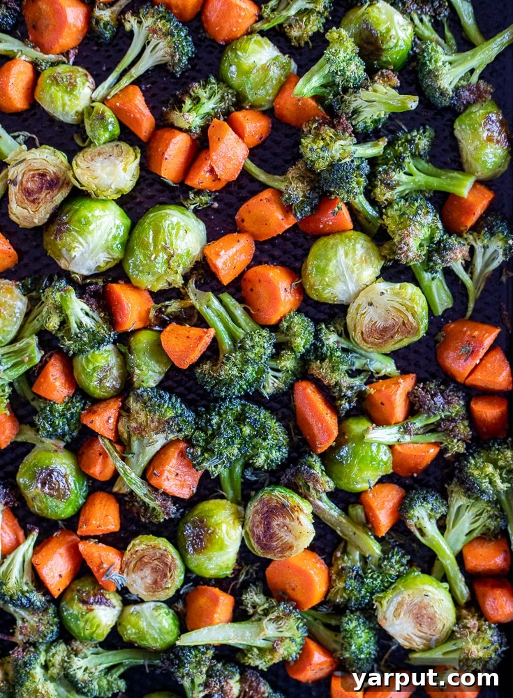 Effortless Roasted Vegetables 6 A baking tray abundantly filled with a vibrant mix of roasted broccoli florets, sweet carrot chunks, and tender Brussels sprouts, all perfectly golden-brown and ready to eat.