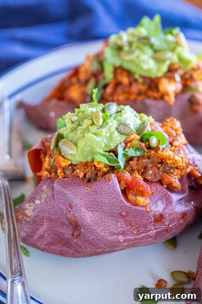 Plant-Powered Sloppy Joe Stuffed Sweet Potatoes 5 A close-up shot of a single vegan sloppy Joe stuffed sweet potato, showcasing its hearty filling and vibrant garnishes.