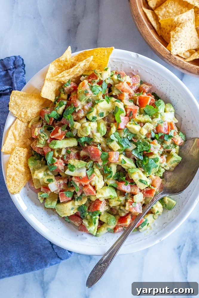 Hearty Avocado Salsa 7 a big bowl of the best avocado salsa with chips and a spoon