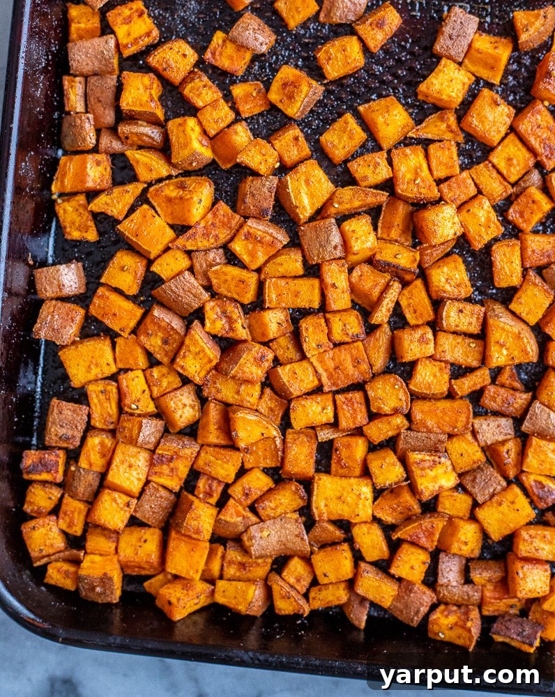 Vibrant Roasted Sweet Potato and Black Bean Kale Power Bowl 3 Close-up of cubed sweet potatoes seasoned with a blend of spices, ready for roasting on a baking tray, highlighting their vibrant orange color.