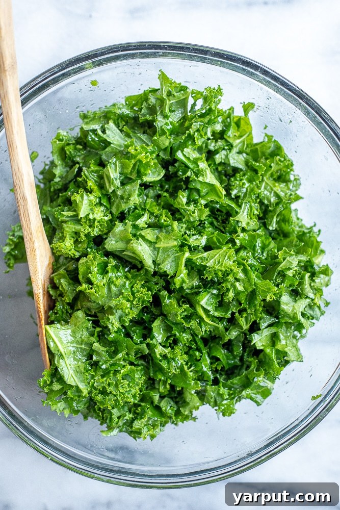 Vibrant Roasted Sweet Potato and Black Bean Kale Power Bowl 4 A large bowl filled with freshly massaged kale, glistening with dressing, ready to be combined with other salad ingredients.