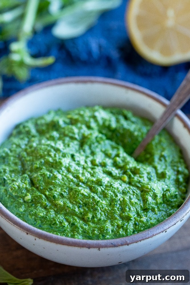 Effortless Vegan Pesto 2 bright green vegan pesto sauce in a bowl with a spoon