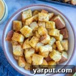 A small bowl of golden, crispy homemade croutons, perfect for adding crunch to salads or soups.