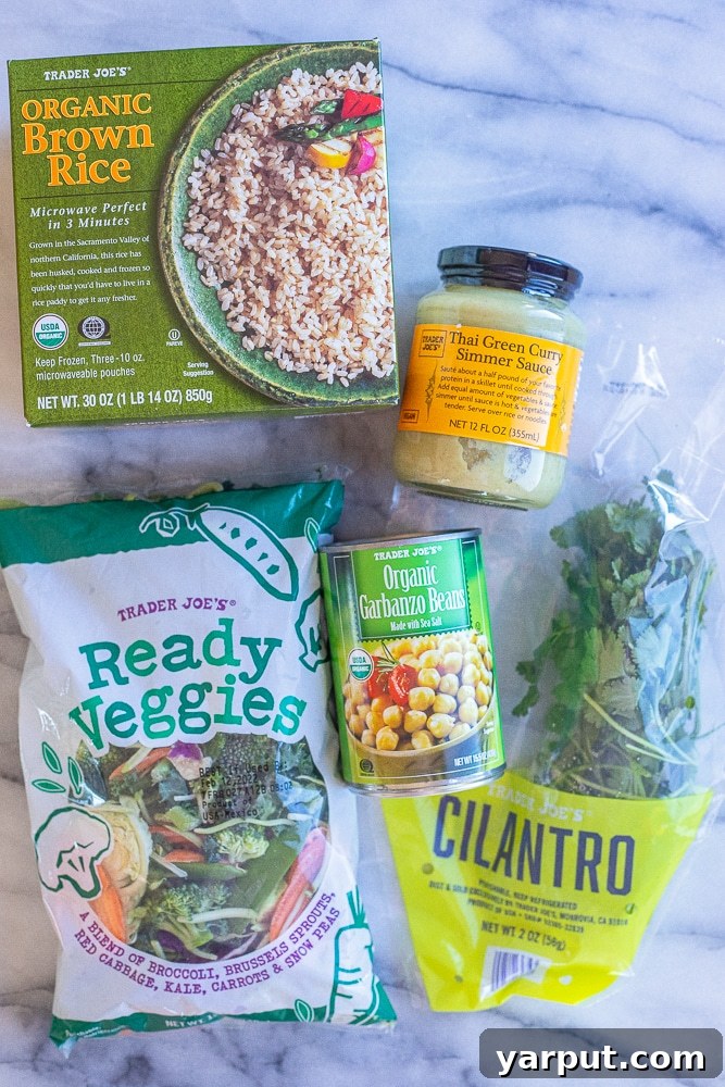 Hearty Chickpea and Vegetable Thai Green Curry 3 All five simple ingredients for Trader Joe's Thai green curry with chickpeas laid out: green curry sauce, canned chickpeas, a bag of stir-fry vegetables, fresh cilantro, and frozen brown rice.