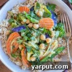 Hearty Chickpea and Vegetable Thai Green Curry 8 A vibrant bowl of Thai green curry with chickpeas, broccoli, and other fresh vegetables served over fluffy brown rice.
