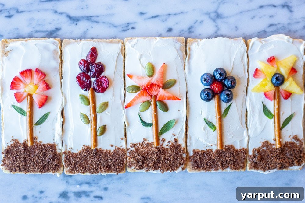 Blooming Graham Gardens 6 Five vibrant flower garden graham crackers are neatly arranged side-by-side on a white marble surface, showcasing their unique and colorful fruit decorations.
