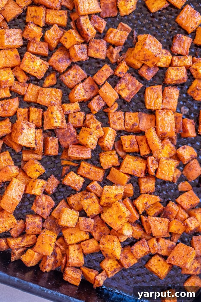 Smoky Chipotle Sweet Potato Salad 3 Diced sweet potatoes seasoned with chipotle and other spices, laid out on a sheet pan, ready for roasting.