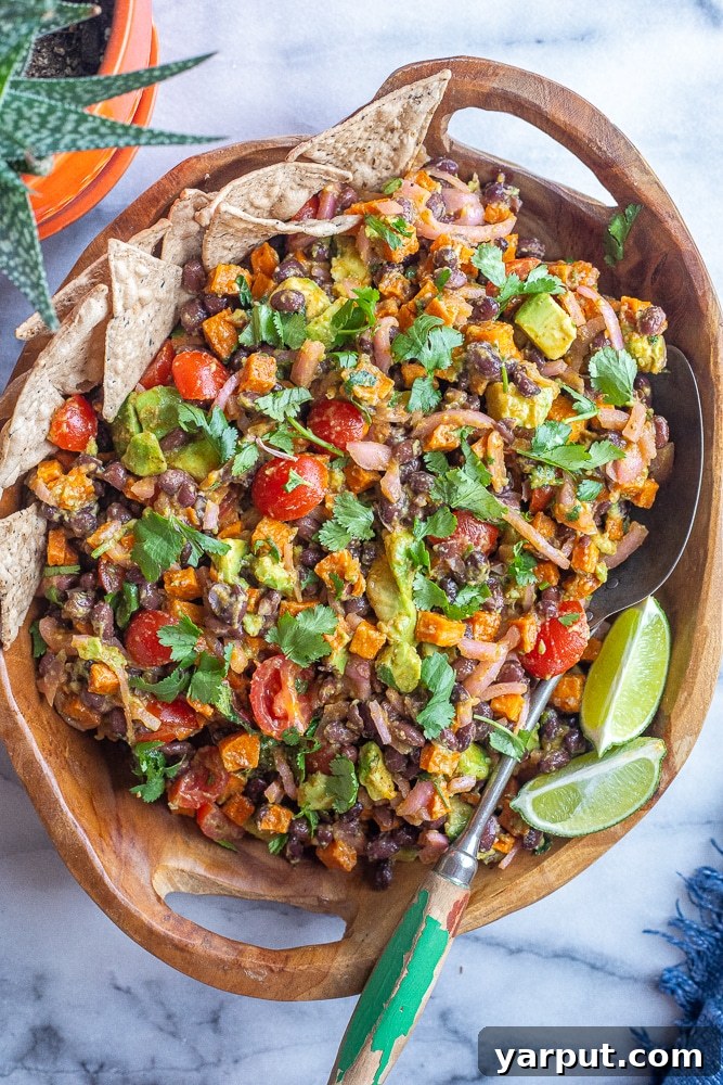 Smoky Chipotle Sweet Potato Salad 6 Chipotle Roasted Sweet Potato Salad in a large wooden bowl, garnished with fresh cilantro, served with a spoon and tortilla chips on the side, ready to be enjoyed.