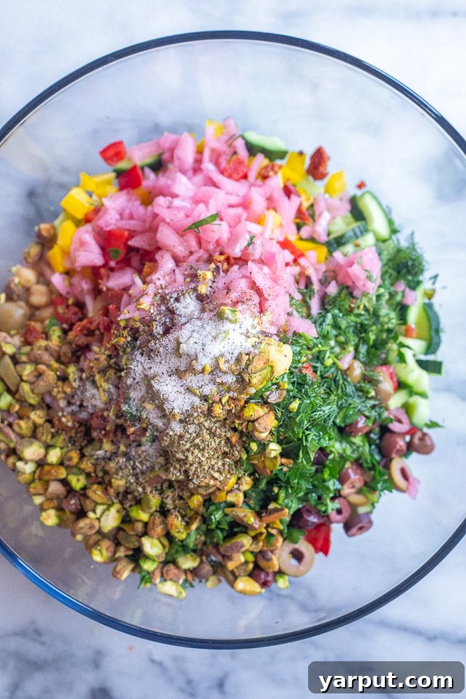 Vibrant Mediterranean Quinoa Bowl 3 All the fresh ingredients for Mediterranean quinoa salad laid out in a bowl before mixing, including cooked quinoa, chickpeas, olives, cucumbers, and tomatoes.