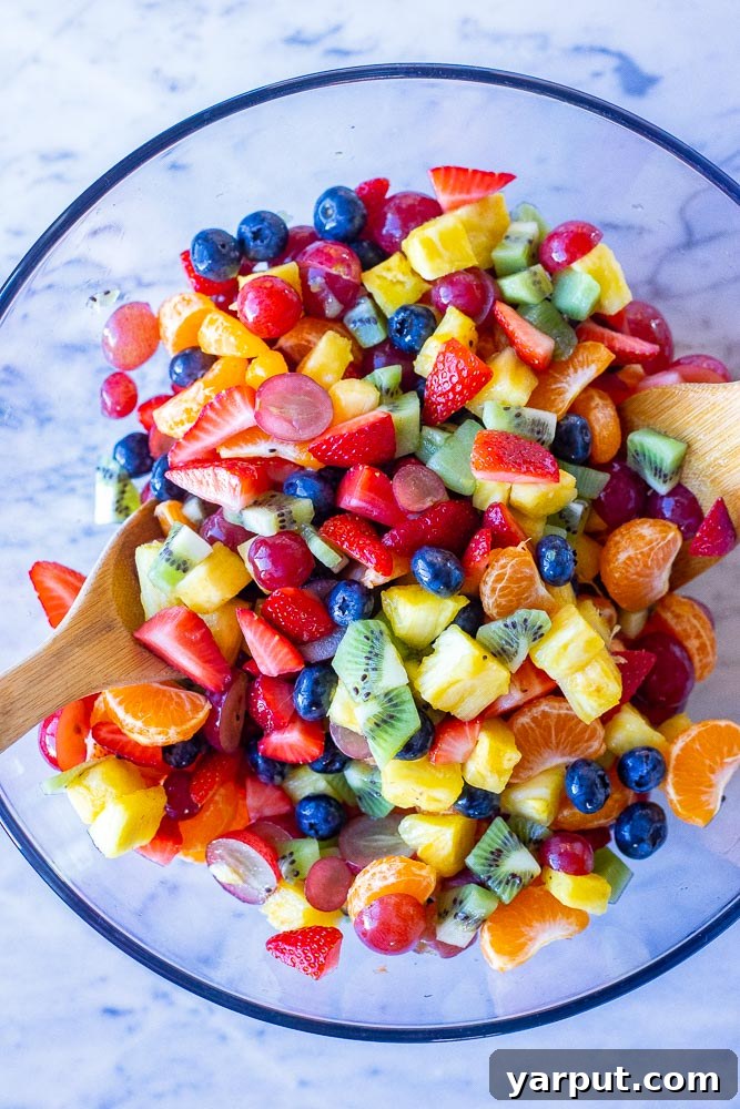 Radiant Rainbow Fruit Salad 4 rainbow fruit salad all mixed together in a bowl with wooden spoons