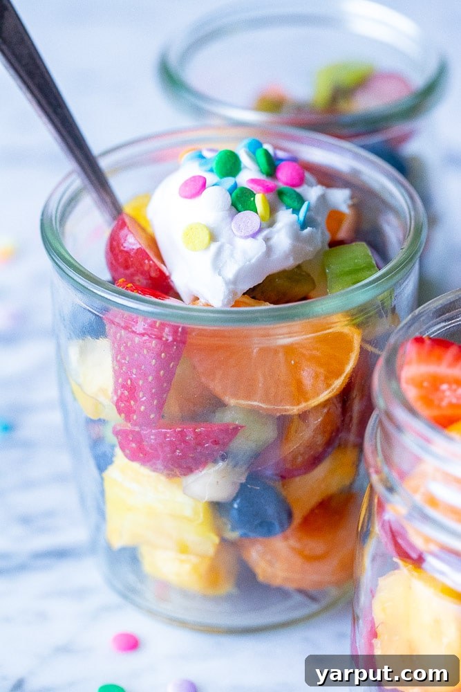 Radiant Rainbow Fruit Salad 6 fruit salad in a cup topped with coconut whipped cream and sprinkles