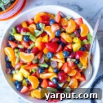 A vibrant rainbow fruit salad in a white bowl