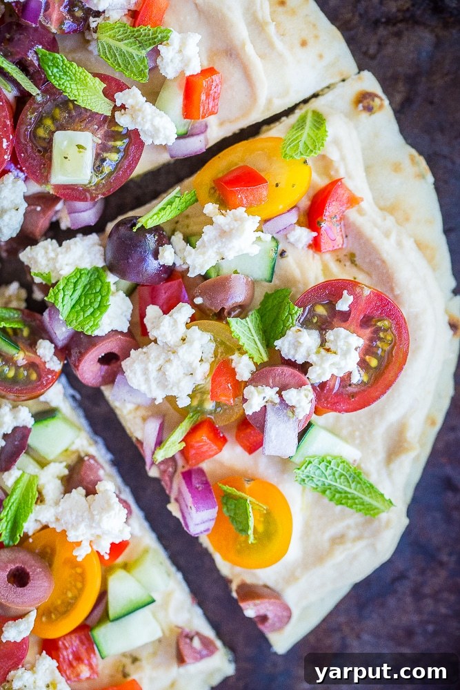 67 Beginner-Friendly Vegan Recipes 26 Easy and fresh no-cook Mediterranean hummus pizzas, topped with vibrant vegetables, olives, and a drizzle of olive oil on pita bread.