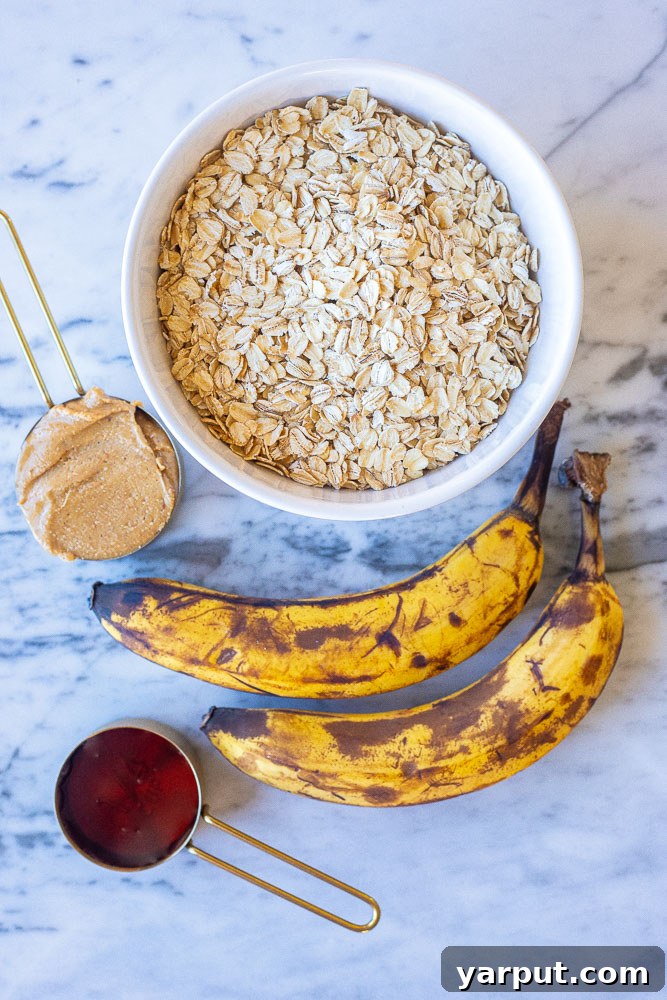 The four simple ingredients: oats, bananas, peanut butter, and maple syrup, laid out on a table