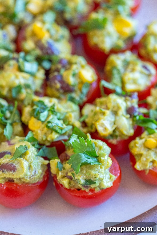 Zesty Guacamole Tomato Bites 5 A beautifully arranged platter of freshly prepared guacamole stuffed tomatoes, garnished with cilantro, ready for serving.