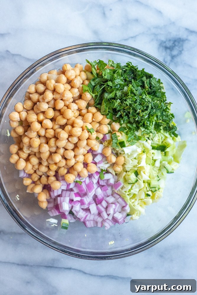 Vibrant Chickpea & Cabbage Medley with Cucumber 3 A bowl showcasing the fresh ingredients of the chickpea salad before mixing, including chickpeas, cucumber, cabbage, and herbs