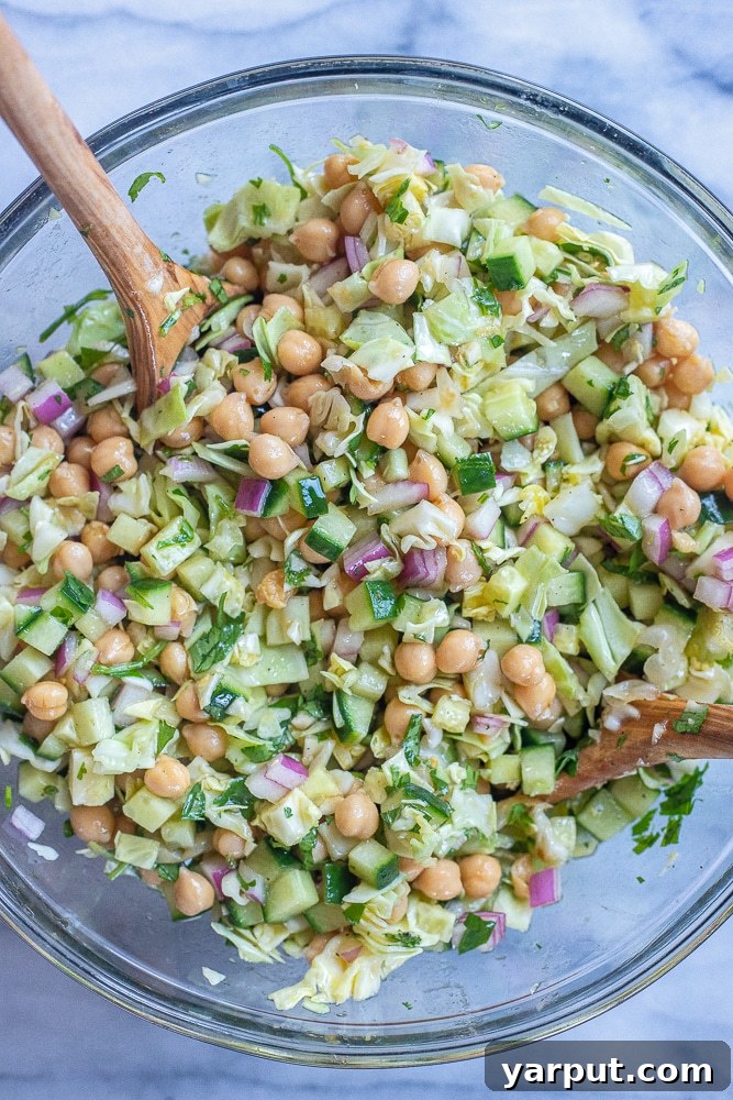 Vibrant Chickpea & Cabbage Medley with Cucumber 4 The vibrant chickpea salad with cucumber and cabbage, mixed with dressing, presented in a large bowl