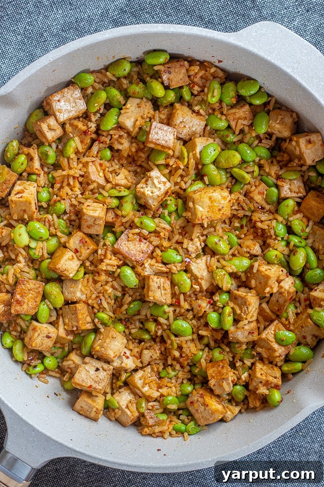 A large, steaming pan filled with freshly cooked edamame stir fry, showcasing its vibrant ingredients and inviting aroma.