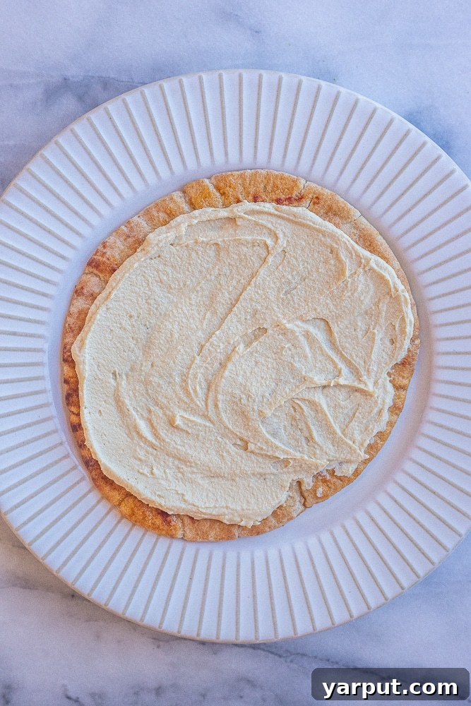 Broccoli Salad Hummus Pita Pockets 4 A freshly prepared pita bread, lavishly spread with a thick layer of creamy hummus, placed neatly on a crisp white plate, perfectly poised and ready to be topped with the vibrant broccoli salad filling.