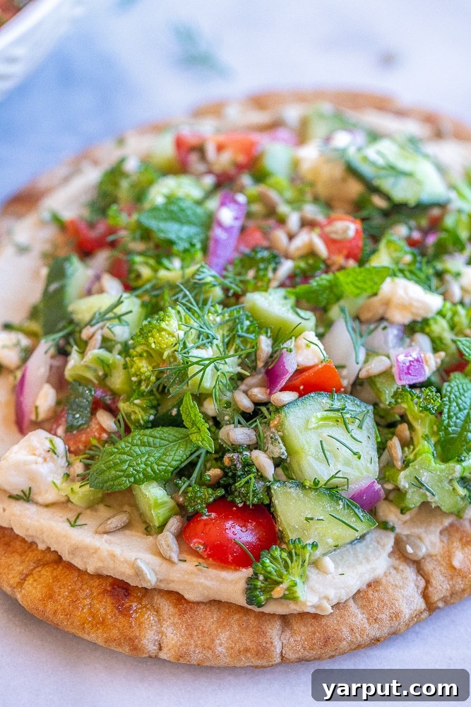 Broccoli Salad Hummus Pita Pockets 5 A captivating close-up photograph showcasing two vibrant Broccoli Salad Hummus Pitas, generously filled with a medley of fresh ingredients and elegantly garnished with roasted sunflower seeds, perfectly highlighting their appetizing textures and rich, inviting colors.