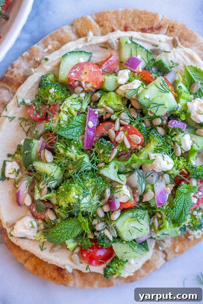 Broccoli Salad Hummus Pita Pockets 6 A stunning visual display of beautifully assembled Broccoli Salad Hummus Pitas, artfully arranged on a rustic cutting board and elegantly surrounded by sprigs of fresh dill and other vibrant herbs, perfectly emphasizing their wholesome appeal and inviting freshness.