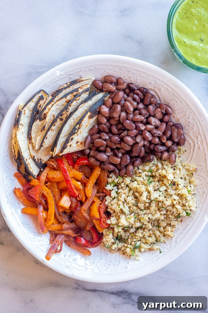 Vibrant Vegan Fajita Bowls with Creamy Avocado Drizzle 5 A beautifully assembled Vegan Fajita Bowl featuring a generous portion of cauliflower rice, sautéed bell peppers and onions, black beans, and a vibrant green avocado sauce.