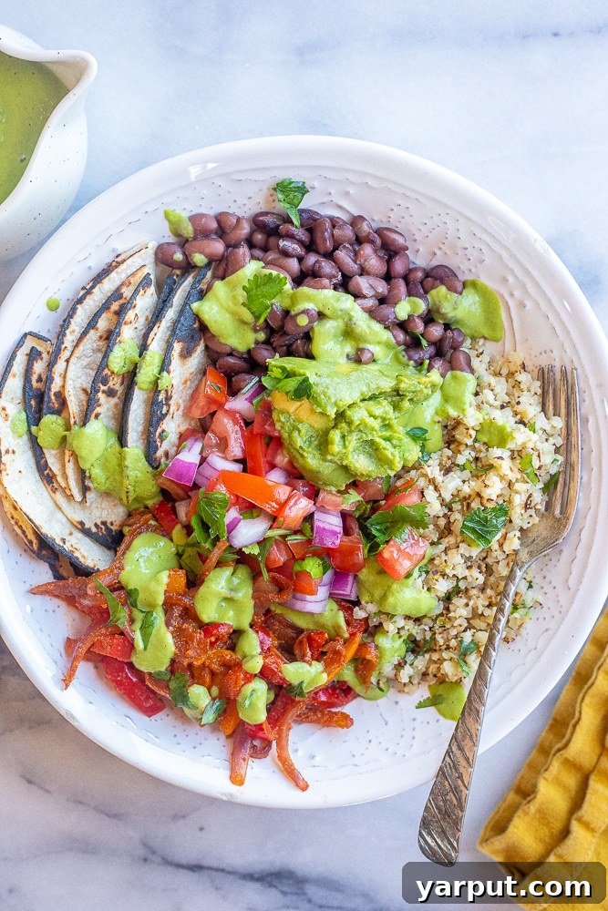 Vibrant Vegan Fajita Bowls with Creamy Avocado Drizzle 6 A close-up of a finished Vegan Fajita Bowl, richly topped with creamy avocado sauce, fresh guacamole, and salsa, highlighting the vibrant colors and textures.