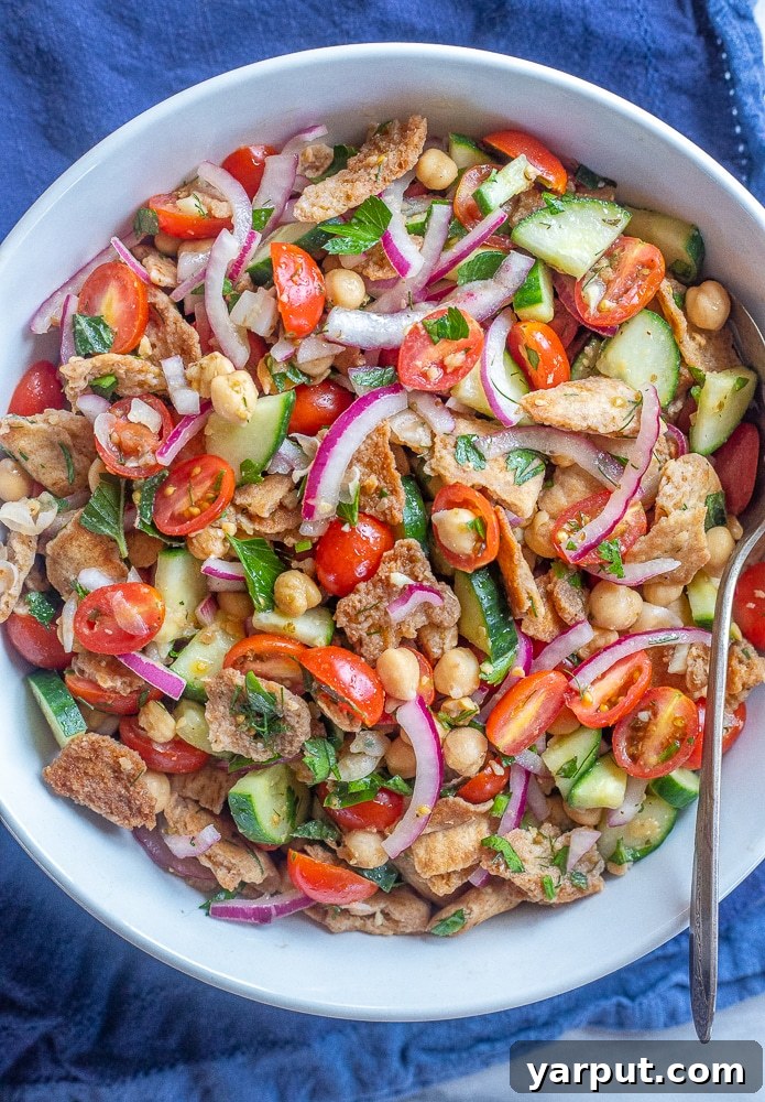 Golden Pita Salad 2 A large bowl filled with vibrant Crispy Pita Bread Salad, featuring golden pita pieces, cherry tomatoes, cucumbers, and fresh herbs.