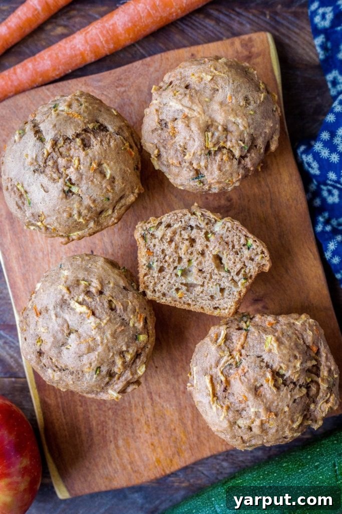 Farmhouse Zucchini Apple Carrot Muffins 5 Delicious zucchini apple carrot muffins artfully arranged on a wooden cutting board, ready to be enjoyed.