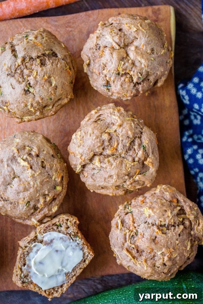 Farmhouse Zucchini Apple Carrot Muffins 6 A close-up of healthy zucchini apple carrot muffins, one spread with a dollop of butter, highlighting their moist and inviting texture.