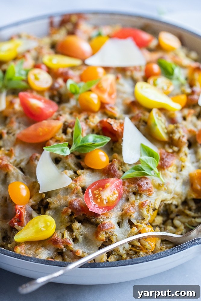 One Pan Pesto Orzo with Burst Cherry Tomatoes and Feta 2 Hearty baked pesto orzo with vibrant cherry tomatoes and crumbled feta cheese in a cast iron skillet, ready to serve.