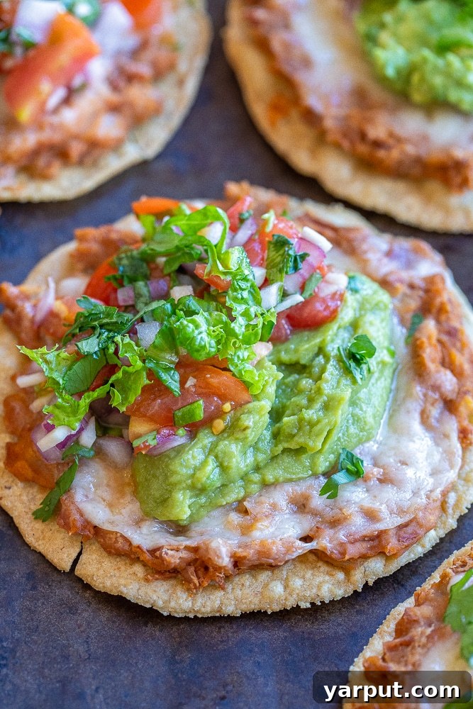Crispy Bean and Cheese Tostadas 5 Close-up view of bean and cheese tostadas with fresh toppings