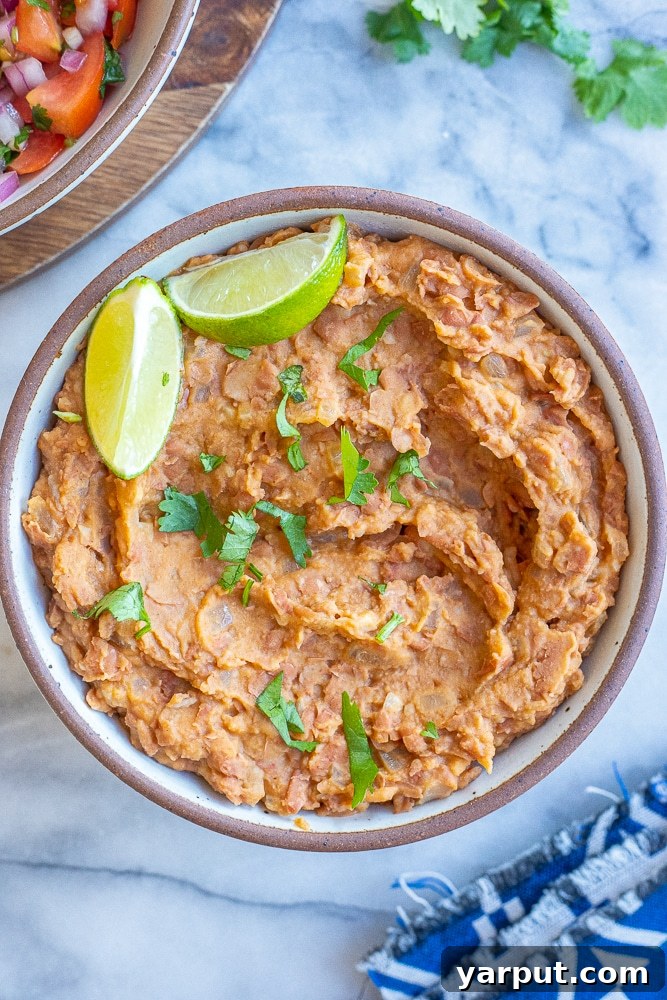 A vibrant bowl of easy homemade refried beans, garnished with cilantro and ready to be enjoyed