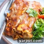 Close up of cheesy zucchini enchiladas on a plate with garnishes.