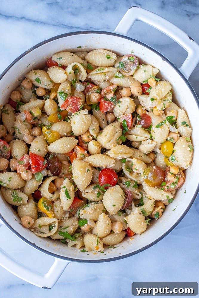 Sun-Kissed Herby Parmesan Tomato Pasta Salad 3 A large pot brimming with Herby Parmesan Tomato Pasta Salad, showcasing perfectly cooked pasta, juicy tomatoes, and wholesome chickpeas before mixing.