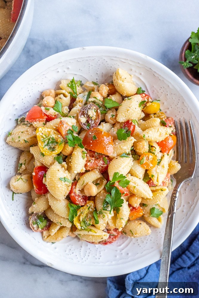 Sun-Kissed Herby Parmesan Tomato Pasta Salad 6 A beautifully set dinner table featuring a large bowl of Herby Parmesan Tomato Pasta Salad, ready to be enjoyed as a family meal.