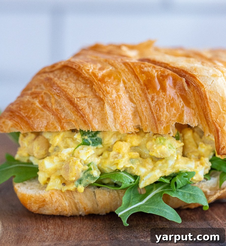 Golden Curried Chickpea & Egg Salad 6 Close-up of a perfectly constructed curried egg salad sandwich with chickpeas, showcasing its creamy texture and fresh ingredients.