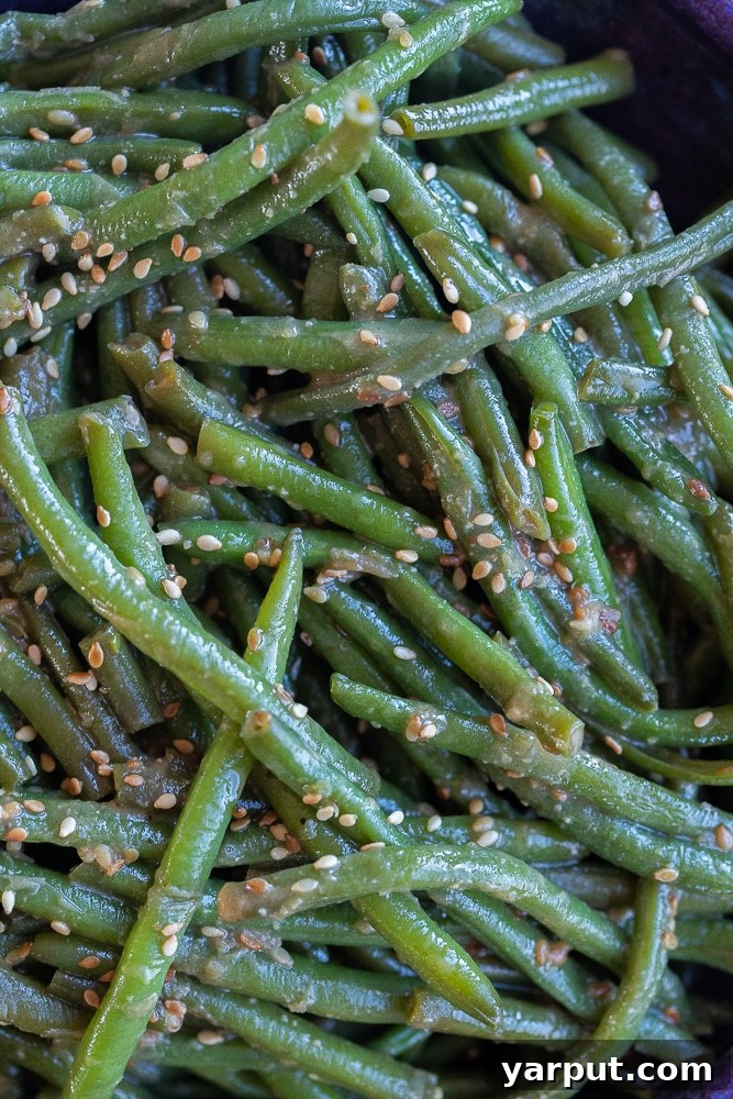 An artistic close-up shot of a small bunch of Miso Sesame Green Beans, showcasing their vibrant color and glossy sauce texture.