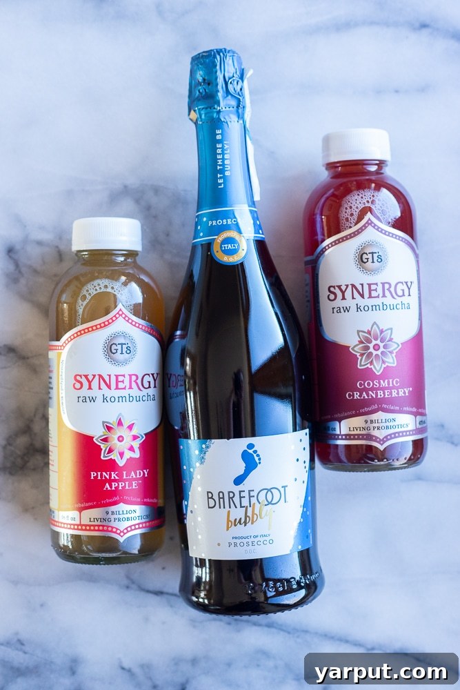 Crisp Apple Cranberry Probiotic Fizz 3 Various ingredients laid out on a table, including bottles of sparkling wine, cranberry kombucha, and apple kombucha, ready to be mixed into delicious kombucha mimosas.