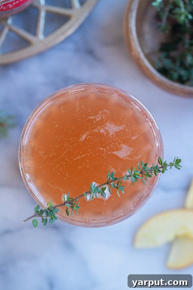Crisp Apple Cranberry Probiotic Fizz 6 A stunning flat lay photograph showcasing several Apple Cranberry Kombucha Mimosas in elegant flutes, adorned with festive garnishes like fresh thyme and cranberries, set against a holiday backdrop.