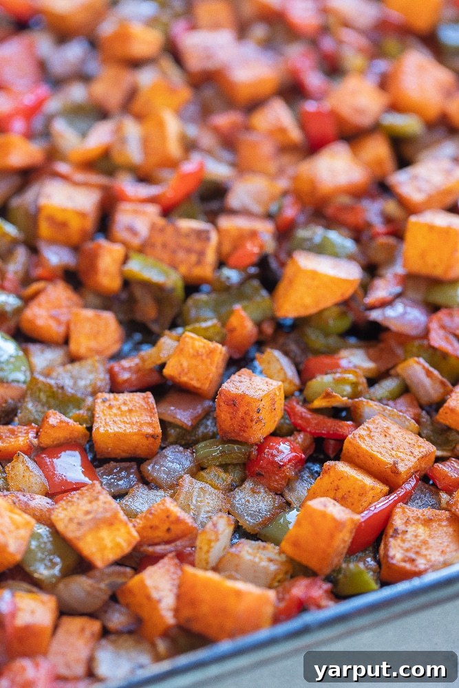 Golden Sweet Potato Skillet 5 A close-up view of roasted sweet potato hash on a sheet pan, showcasing the delicious charred edges and tender interior of the vegetables after roasting.
