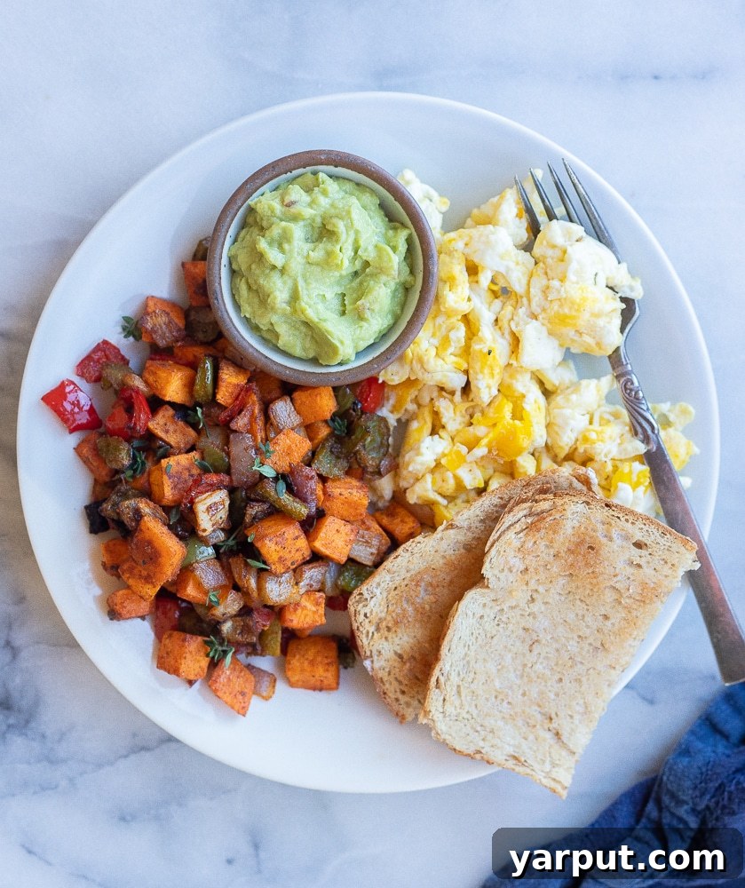 Golden Sweet Potato Skillet 6 A vibrant breakfast plate featuring roasted sweet potato hash, served alongside fluffy scrambled eggs, perfectly toasted bread, and creamy avocado slices, highlighting a complete and delicious meal.