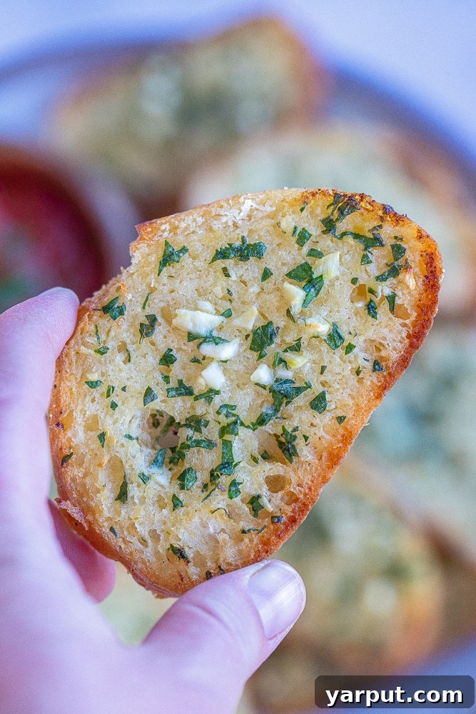 Umami Garlic Crisps with Miso Butter 6 close up of a hand holding a slice of thin and crispy garlic bread