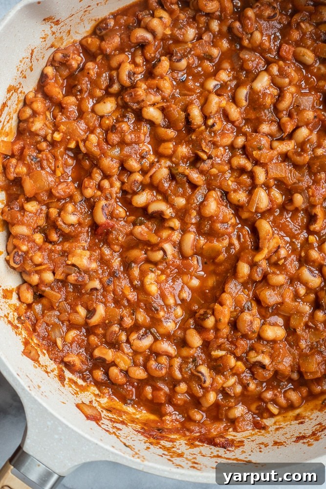 Smoky BBQ Black-Eyed Peas 3 BBQ Black Eyed Peas simmering in a pan, a close-up shot showing rich sauce and tender beans.