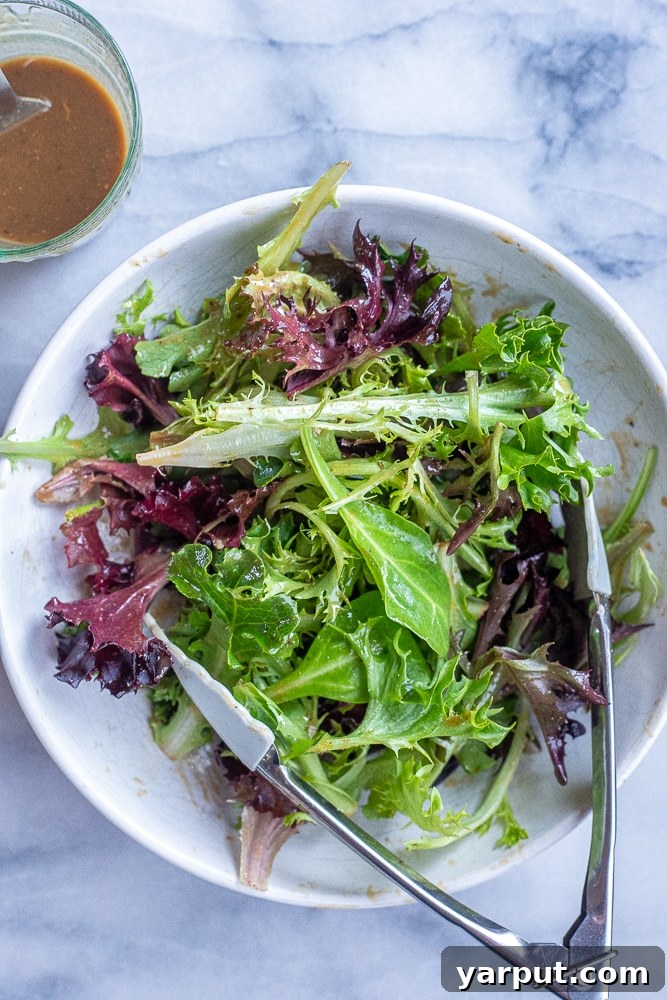 Zesty Roasted Veggie Hummus Wraps with Crumbled Feta 4 A vibrant bowl of mixed salad greens lightly coated with a homemade balsamic dressing, ready to be added to the wraps.