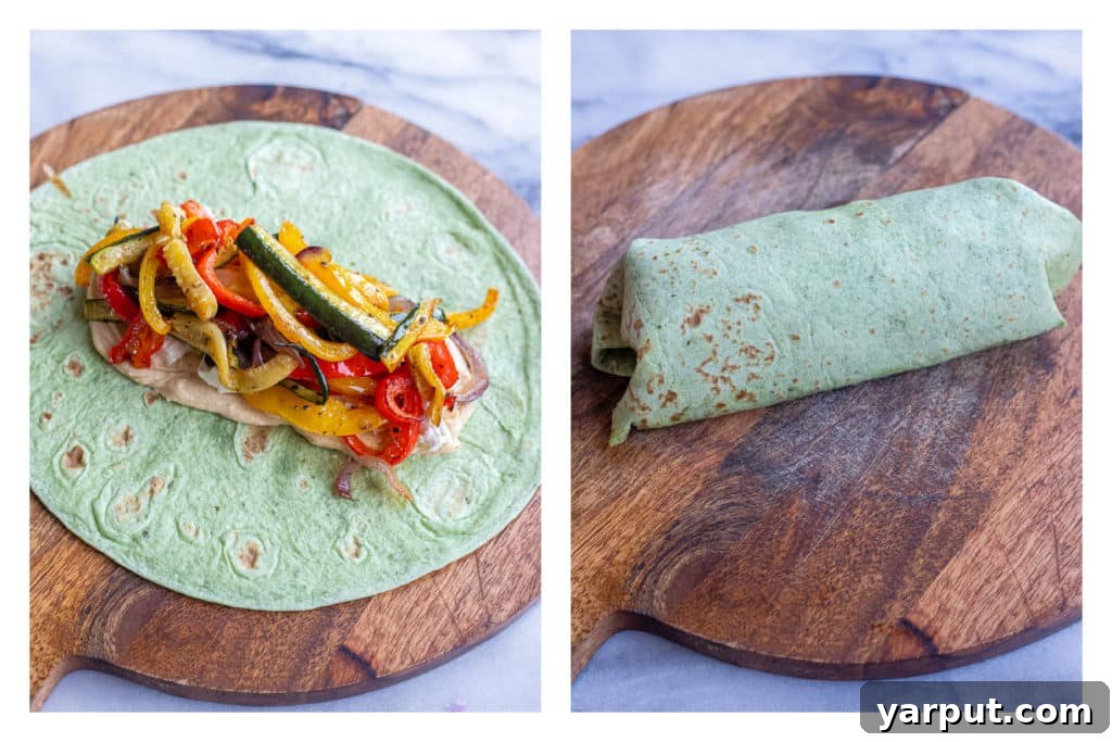 Zesty Roasted Veggie Hummus Wraps with Crumbled Feta 5 A freshly assembled roasted vegetable hummus wrap, rolled up tightly with its colorful filling visible, ready to be sliced.