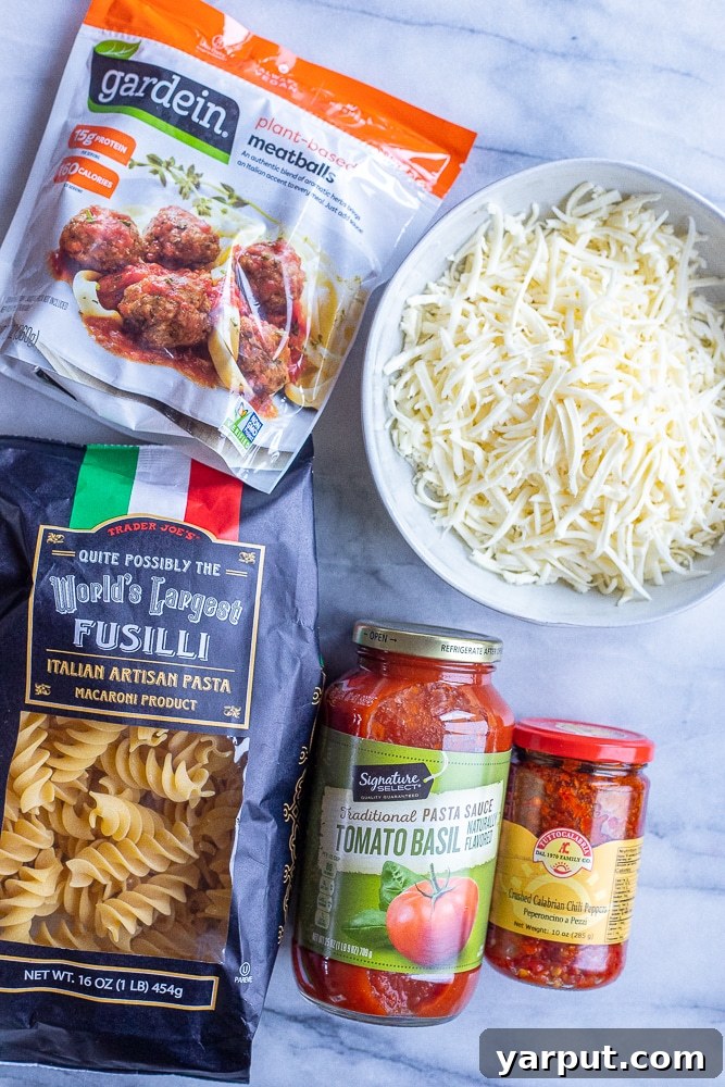 Boldly Spiced Baked Pasta and Plant-Powered Meatballs 3 Close-up of the five essential ingredients for spicy baked pasta: pasta, vegetarian meatballs, pasta sauce, a jar of Calabrian chili peppers, and shredded cheese