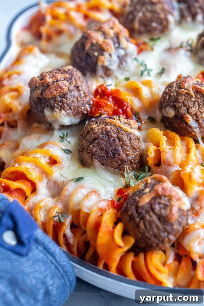 Boldly Spiced Baked Pasta and Plant-Powered Meatballs 6 A close-up shot of a vegetarian meatball nestled in the spicy baked pasta, showcasing the rich sauce, melted cheese, and pasta texture
